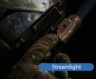 Ręka w rękawicy taktycznej trzyma pistolet z latarką STREAMLIGHT w ciemnym, kamiennym otoczeniu.